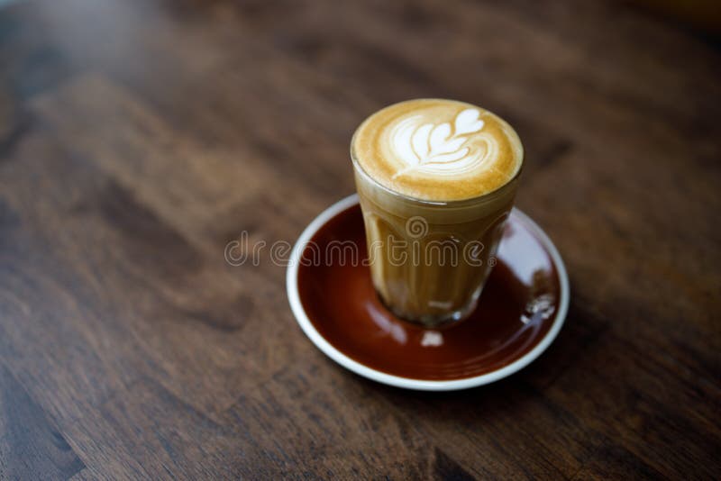Small Cup of Coffee with Heart Pattern Froth on Wooden Table Stock