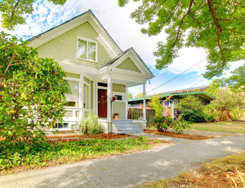 Small cute craftsman American house wth green and white and red door.