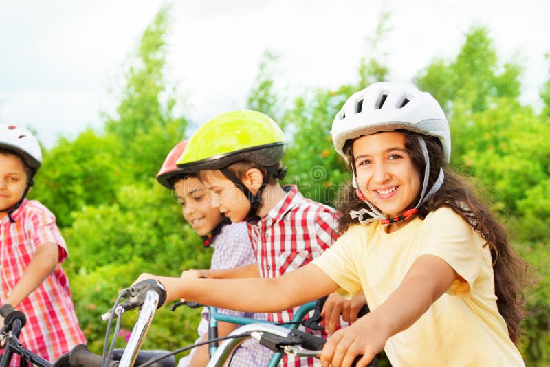 Small cute girl in helmet holds bike handle-bar