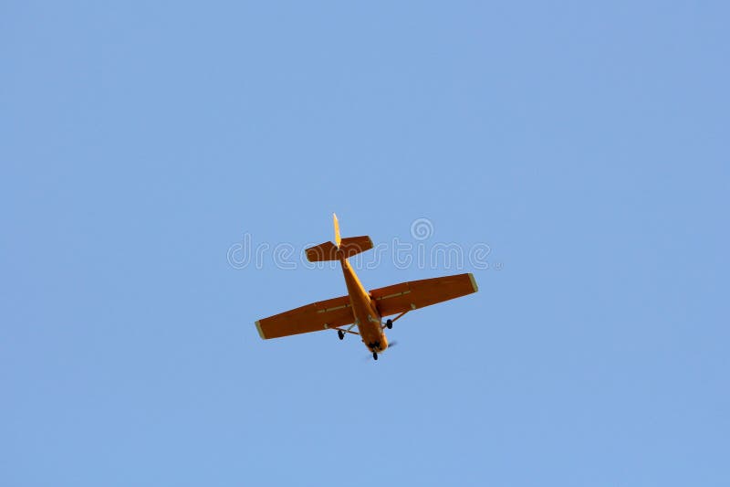 Small dark yellow plane used for panoramic flights flying high in air above local urban area. On clear blue sky background stock photos Small dark yellow plane used for panoramic flights flying high in air above local urban area. On clear blue sky background stock photos