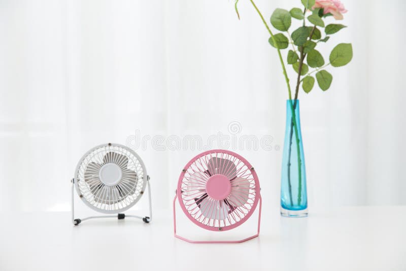 Small desk USB 4 blades cooling fans on a white table with roses in the background royalty free stock photo