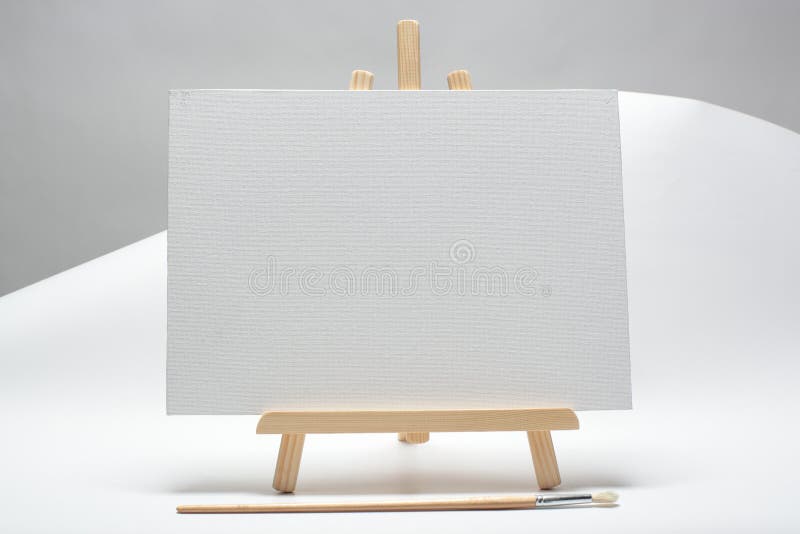 Small Easel with White Blank Cloth on a Wooden Table. Miniature