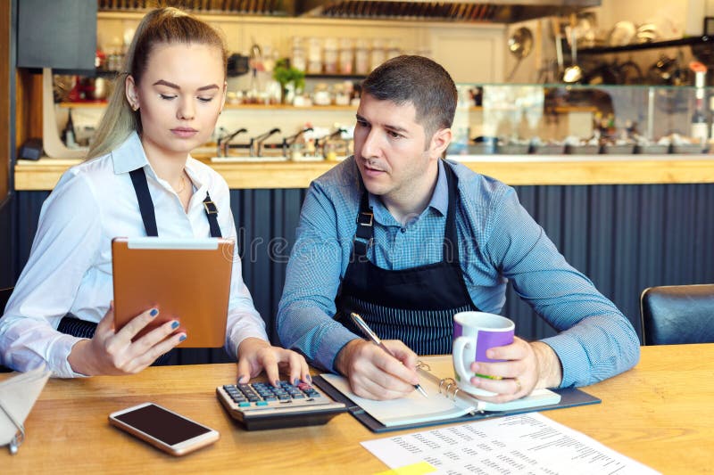 Small family restaurant owners discussing finance calculating bills and expenses of their new small business. stock photo Small family restaurant owners discussing finance calculating bills and expenses of their new small business. stock photo