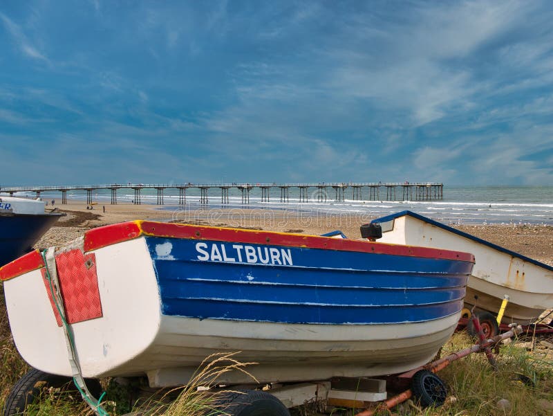 With a small fishing boat in the foreground, a view of the Victorian, Grade 2 listed pier at Saltburn-by-the-Sea, UK