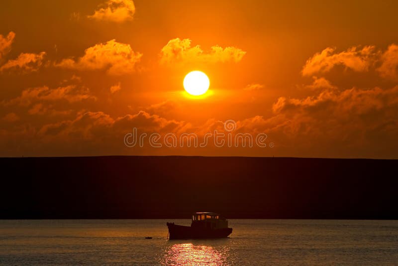 Small fishing boat on its way out to sea at sunset