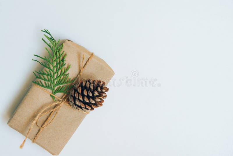 Small Gift Box Wrapped in Craft Paper with Juniper Twig and Pine Cone on White Background. Christmas New Years Presents Shopping royalty free stock images Small Gift Box Wrapped in Craft Paper with Juniper Twig and Pine Cone on White Background. Christmas New Years Presents Shopping royalty free stock images