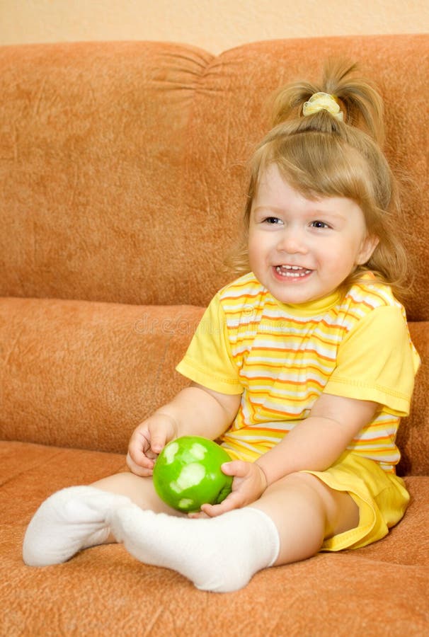 Small girl in yellow eat green apple