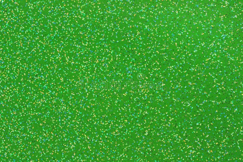 Macro photo of small gold, aqua, black, and white glitter on a green background. Macro photo of small gold, aqua, black, and white glitter on a green background.