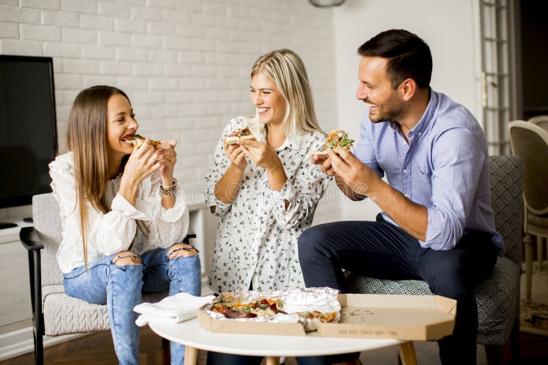 Small group of young friends eating pizza in the room royalty free stock photos Small group of young friends eating pizza in the room royalty free stock photos
