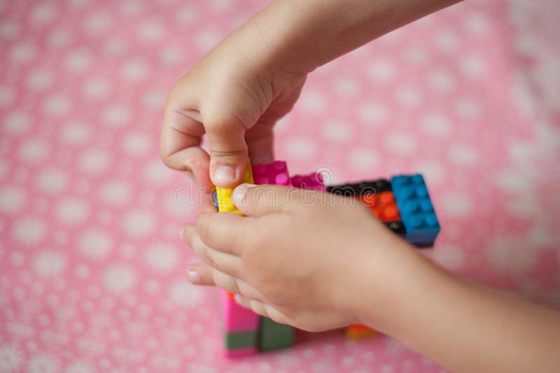 Small Hands of the Child Collects the Bright Plastic Colored Designer