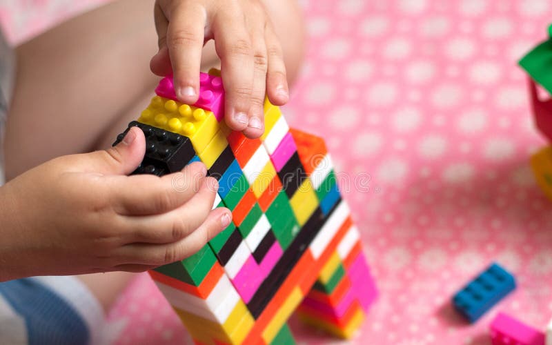 Small hands of the child collects the bright plastic colored Designer. Educational toys and Early learning stock photo
