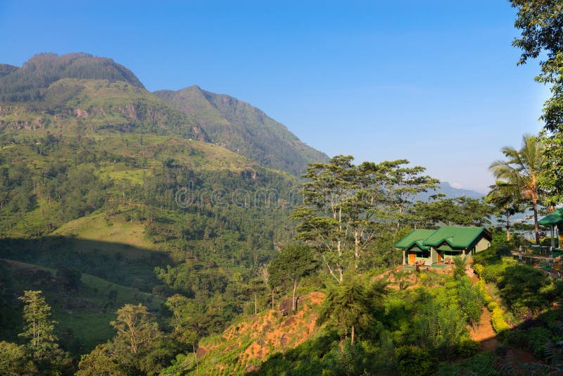 Small house on a green hill at mountains