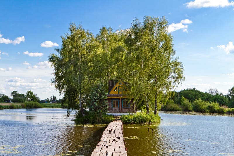 Small house one the island. Landscape with bridge to the house on lake. Old wooden fisherman`s and hunter`s house on the island.