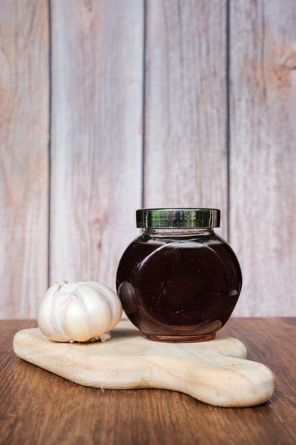 Small Jar of Honey and Garlic on Wooden Background. Garlic on Wooden Background Stock Image
