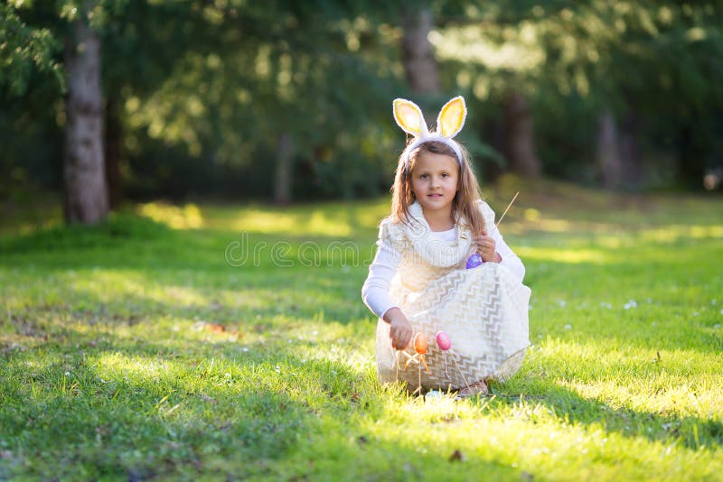 Small little Caucasian girl with Easter bunny ears, s playing with Easter egg pop sticks, looking straight forward to the camera stock photography Small little Caucasian girl with Easter bunny ears, s playing with Easter egg pop sticks, looking straight forward to the camera stock photography