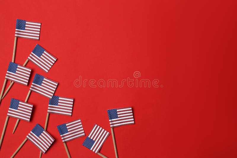 Small paper flags of USA on red background, flat lay. Space for text royalty free stock photo