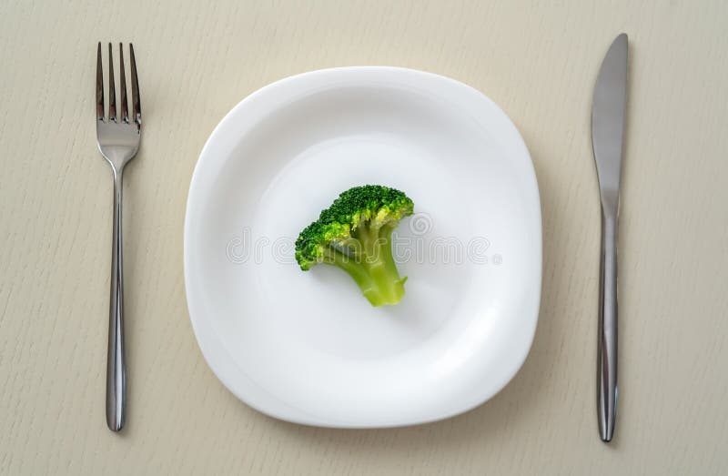 A Small Portion of Boiled Broccoli on a White Plate with a Knife and