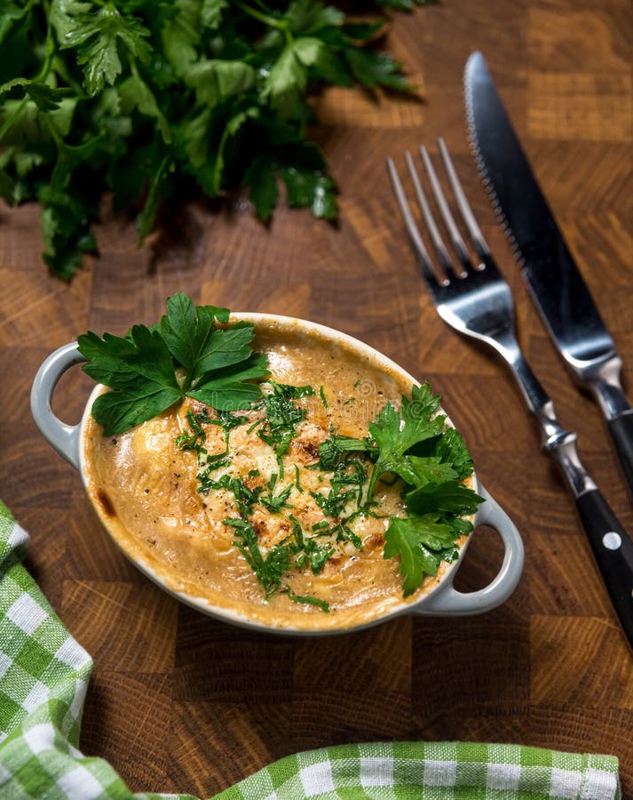 A small portion of creamy Russian julienne with mushrooms and cheese, garnished with parsley leaves. On a wooden table, a bunch of stock photos A small portion of creamy Russian julienne with mushrooms and cheese, garnished with parsley leaves. On a wooden table, a bunch of stock photos