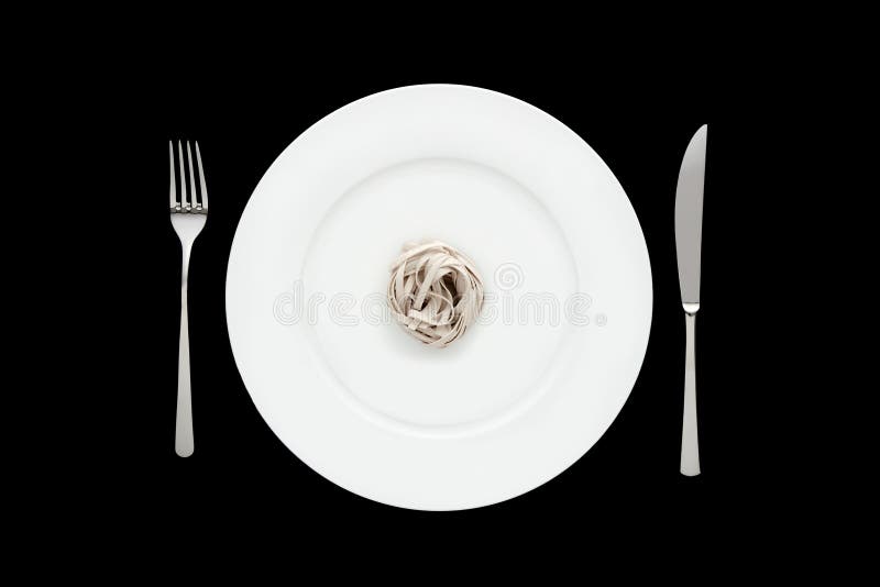 Small portion of tagliatelle pasta on round white plate with fork and knife on isolated black background. royalty free stock photos Small portion of tagliatelle pasta on round white plate with fork and knife on isolated black background. royalty free stock photos