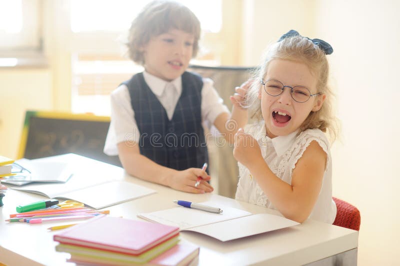 Small pupils, boy and girl, sitting at his desk. stock photo