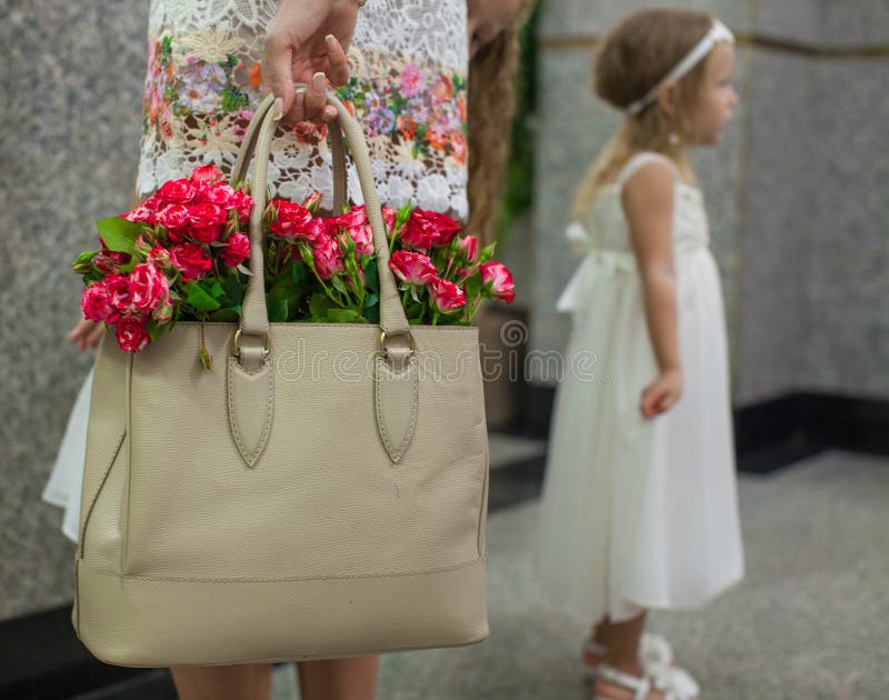 Small red charming roses in fashion women's bag in stock photos Small red charming roses in fashion women's bag in stock photos
