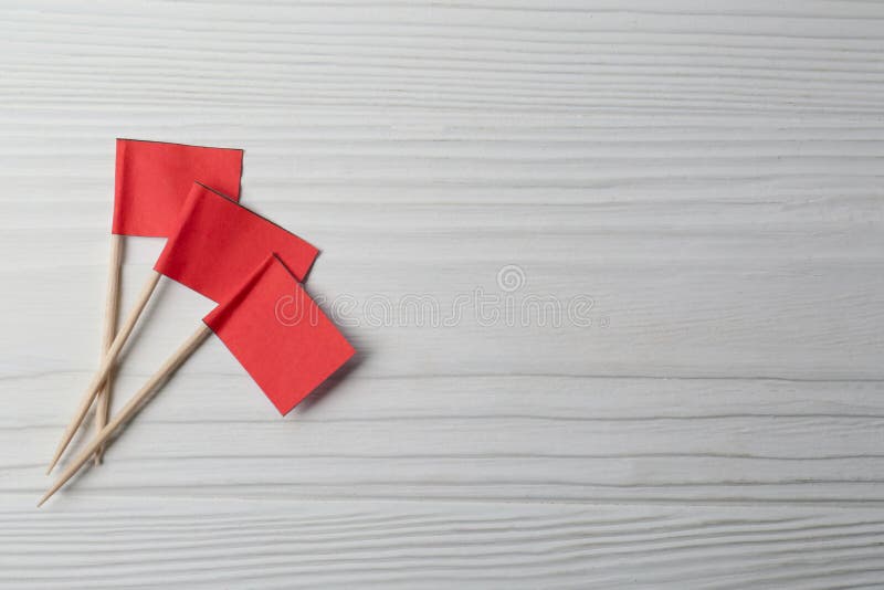 Small red paper flags on white wooden table, flat lay. Space for text royalty free stock photography