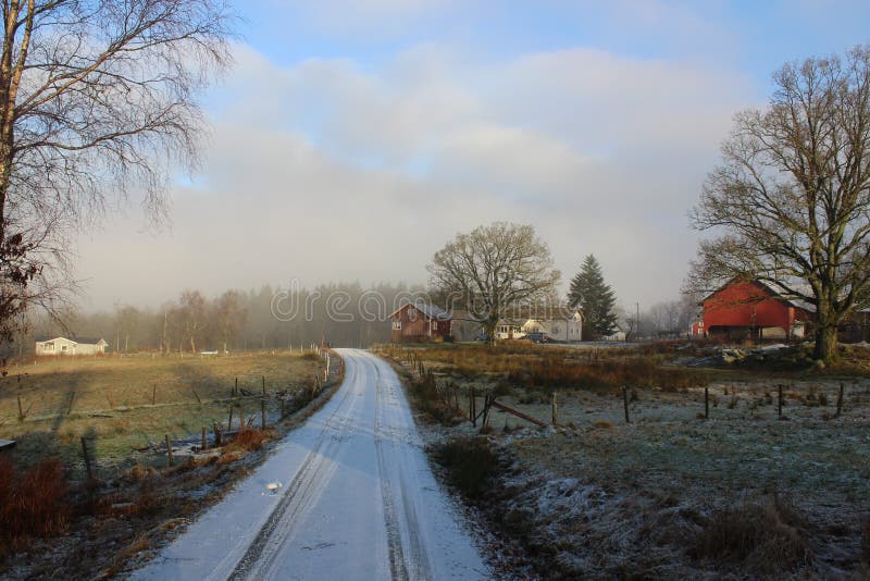 A winter's day in Västra Götaland, Sweden. A small road passing through the fields, meadows and farmlands in the Swedish countryside. A winter's day in Västra Götaland, Sweden. A small road passing through the fields, meadows and farmlands in the Swedish countryside.