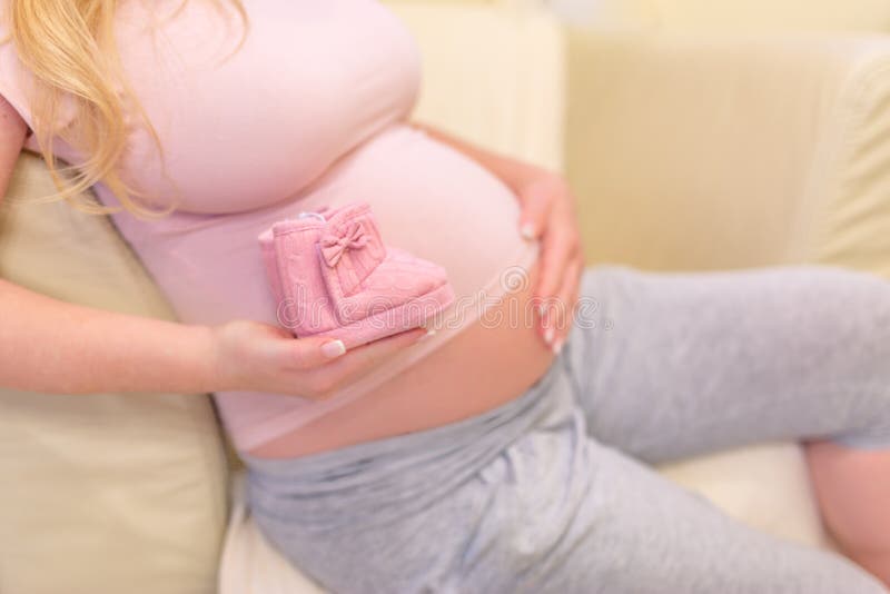 Small shoes for the unborn baby in the belly of pregnant woman royalty free stock photo Small shoes for the unborn baby in the belly of pregnant woman royalty free stock photo