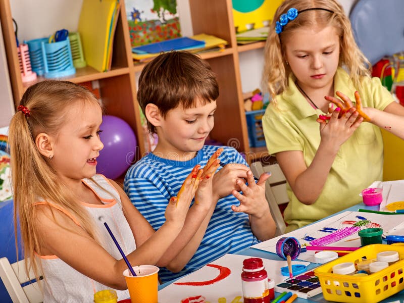 Small students girl finger painting in art school class. Small students with teacher finger painting in art school class. They get their hands dirty in the royalty free stock photos