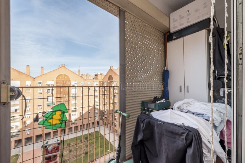 A small terrace of a house with a clothesline full of clothes and a metal railing stock photography