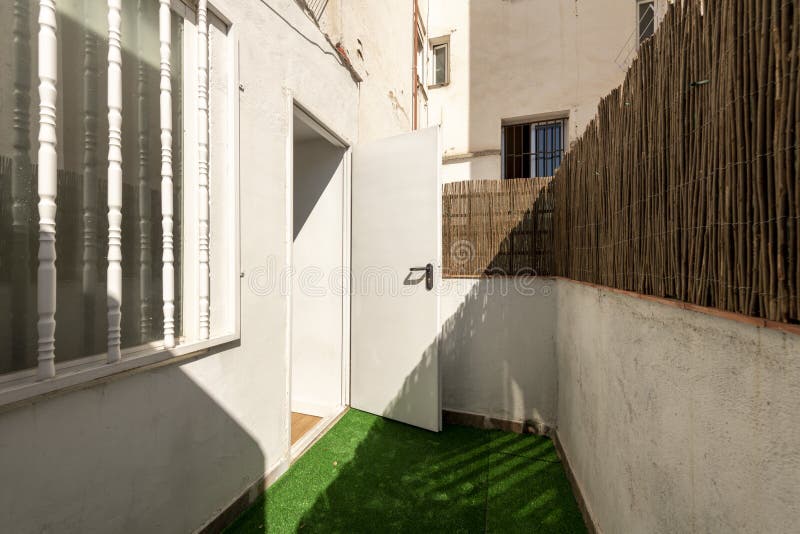 Small terrace of a house on the ground floor with artificial grass floor and reeds to hide from view royalty free stock image