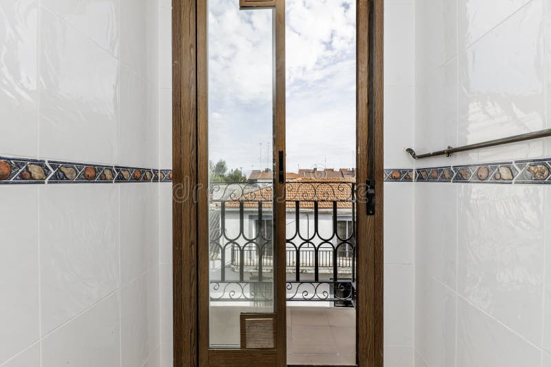 Small terrace with wrought iron railing, with wood-look aluminum access doors in a corner of a small kitchen stock photography