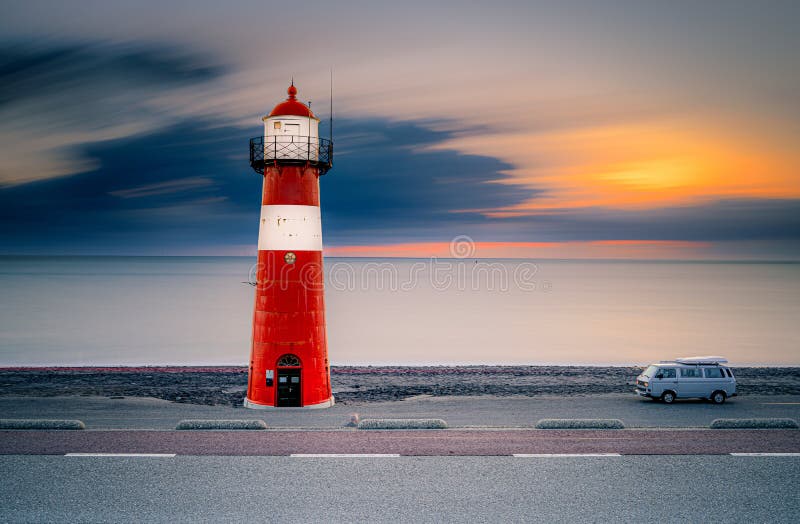 Traditional red and white colored lighthouse against twilight along the Dutch coastline at night