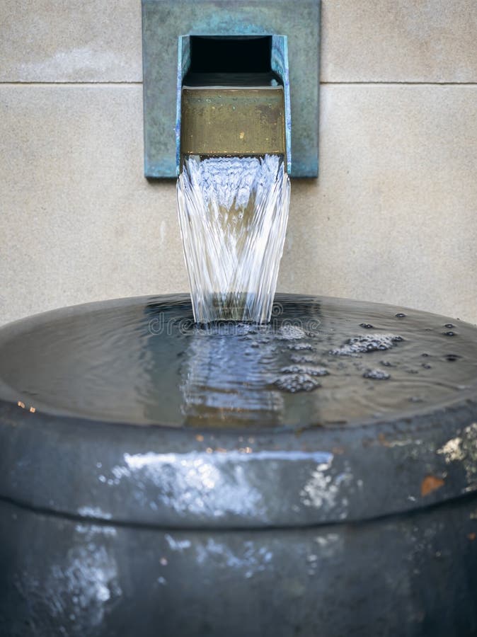 A small water spout forming an artificial waterfall feature