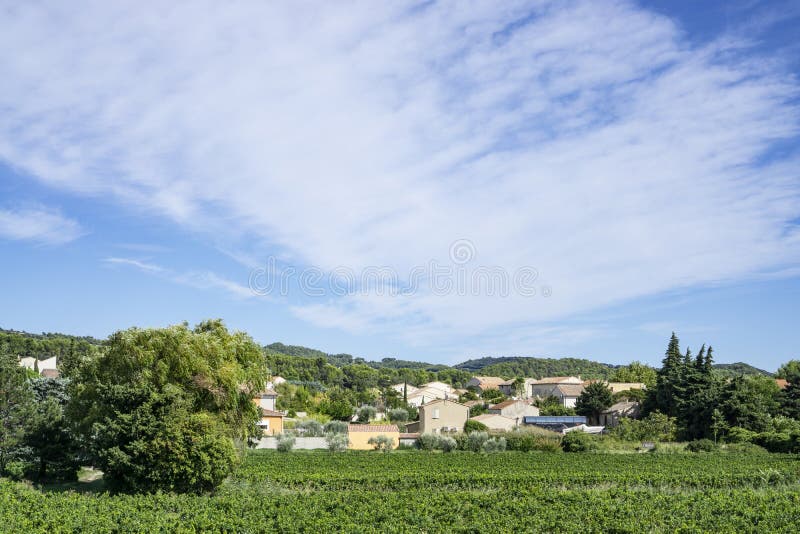 Small wave of beautiful white fluffy clouds on vivid blue sky in a summer time above houses on the mountain, vineyard