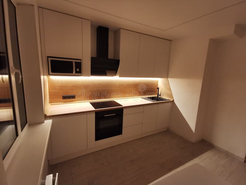 Small white kitchen interior. Modern minimalist apartment in white with black and wood elements. royalty free stock image