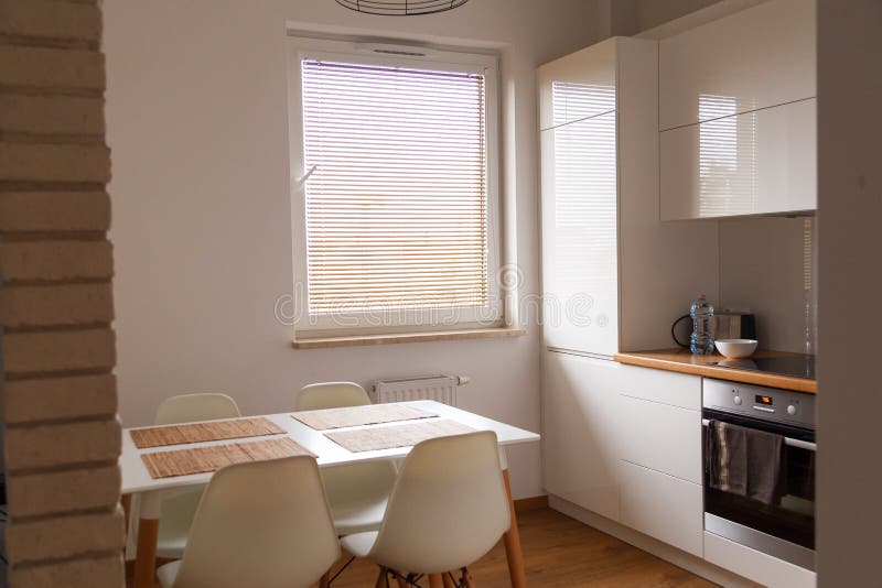 Small, White Kitchen with Table and New Design Chairs Stock Photo