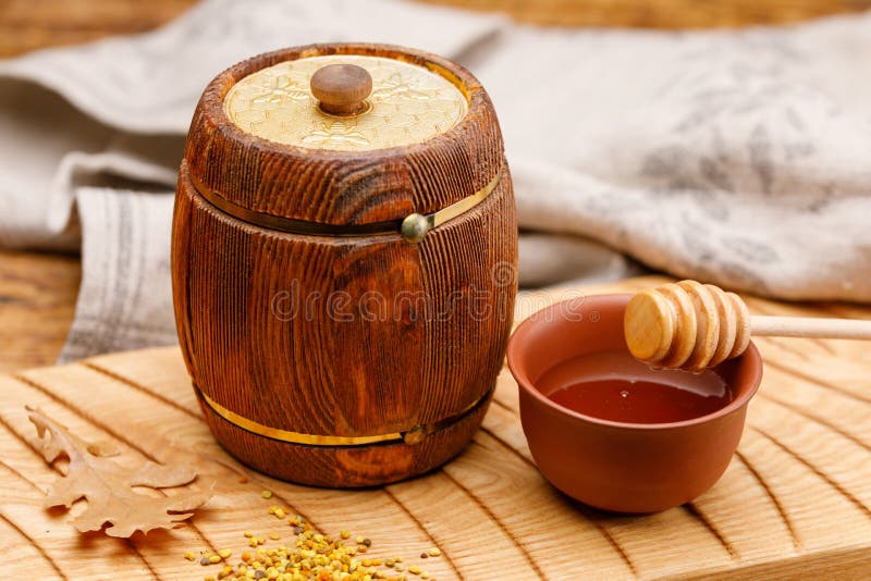 A Small Wooden Barrel with Honey Inside and a Spoon on a Wooden Table. Barrel. Rustic Still Life