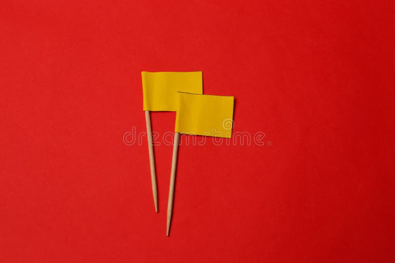 Small yellow paper flags on red background, flat lay royalty free stock photography