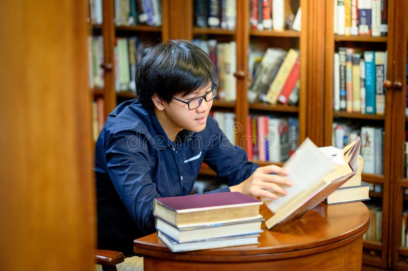 Smart Asian Man Student Reading Book In Library Stock Photo