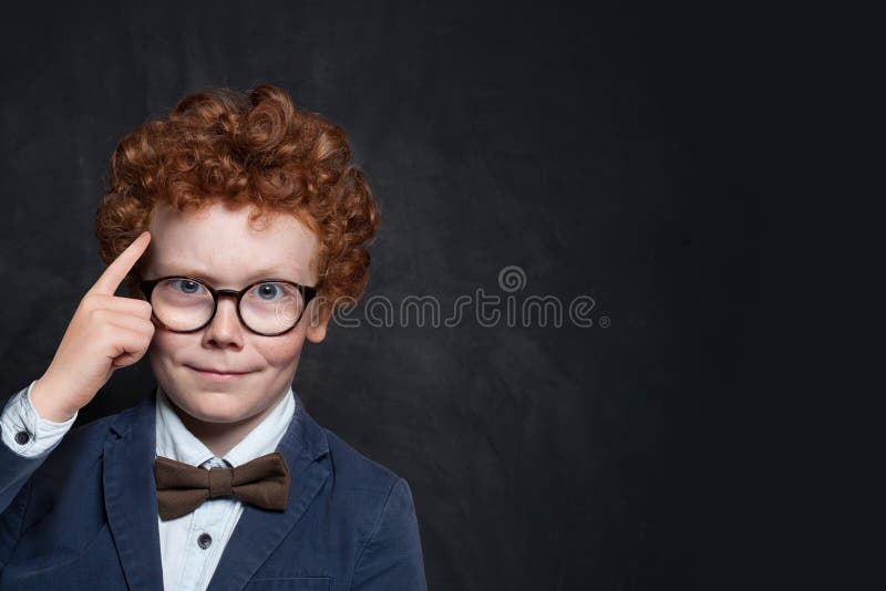 Smart child thinking on blackboard background. Brainstorming and idea concept