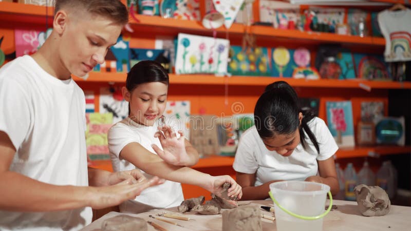 Smart student using hand press on clay piece at pottery workshop. Edification stock video footage