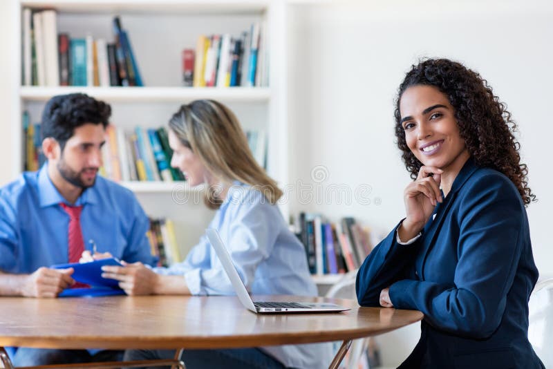 Smart latin american female programmer working at computer at desk stock photography