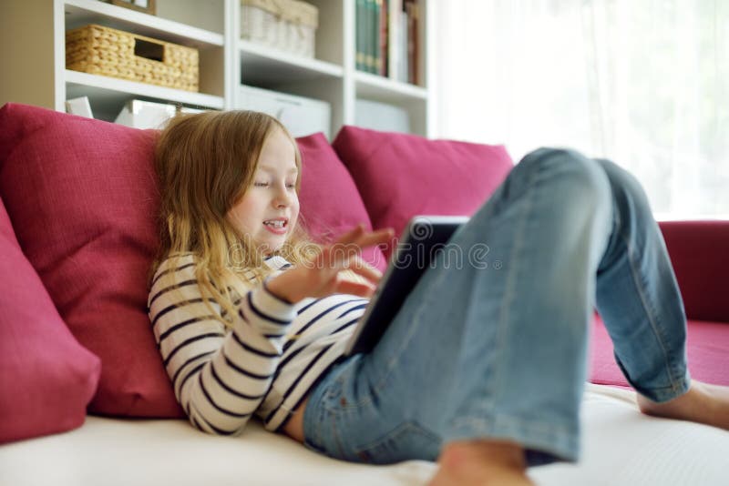 Smart liten skolflicka med digital surfplatta hemma. barn som använder gadgets för att studera. Utbildning och distansundervisning arkivbild