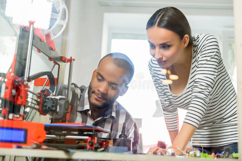 Smart man och kvinna som håller ögonen på printing 3d arkivfoton Smart man och kvinna som håller ögonen på printing 3d arkivfoton