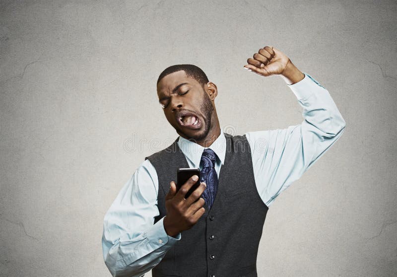 Closeup portrait sleepy young business man, funny guy stretching, yawning, looking at smart phone being bored by phone conversation, texting black background. Facial expression, body language. Closeup portrait sleepy young business man, funny guy stretching, yawning, looking at smart phone being bored by phone conversation, texting black background. Facial expression, body language