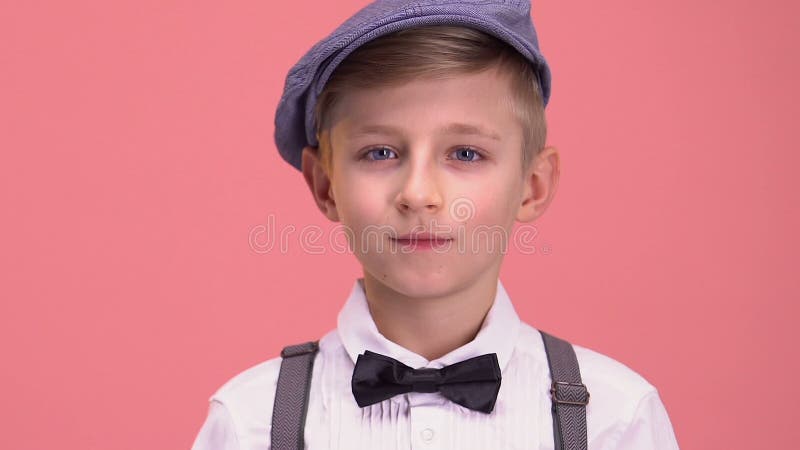 Smart pojke i retro kläder som ser in i kameran som isoleras på rosa bakgrund stock video