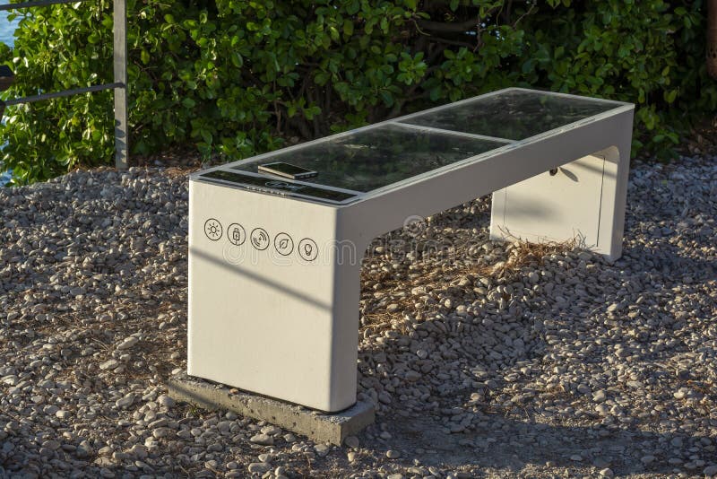 Smart Solar Bench in public place, powered by sunlight provides wireless and wired charging for users, free wifi and temperature royalty free stock image.