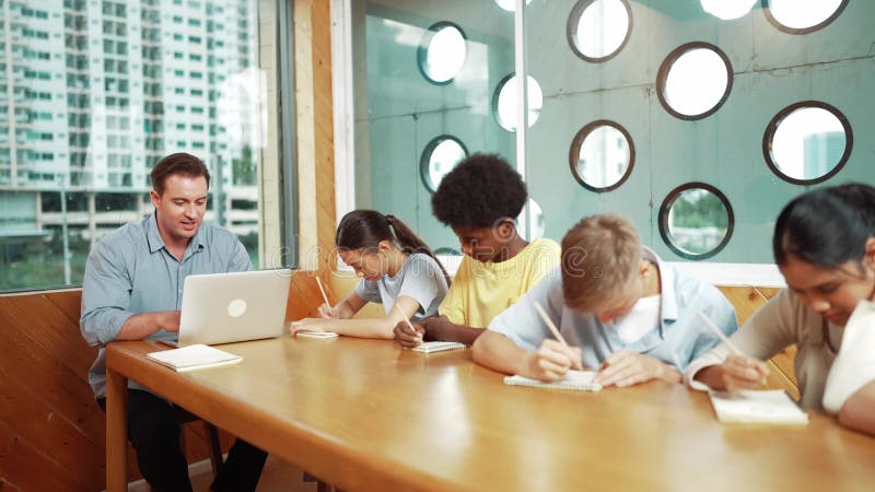 Smart teacher answer question while diverse student doing test. Edification stock footage