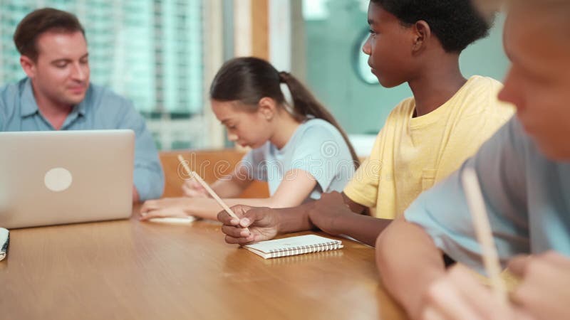 Smart teacher answer question while diverse student doing test. Edification stock video footage